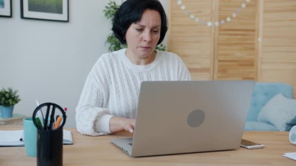 Zestresowana kobieta pracuje z laptopem, a następnie dotyka głowy uczucie bólu głowy w domu — Wideo stockowe