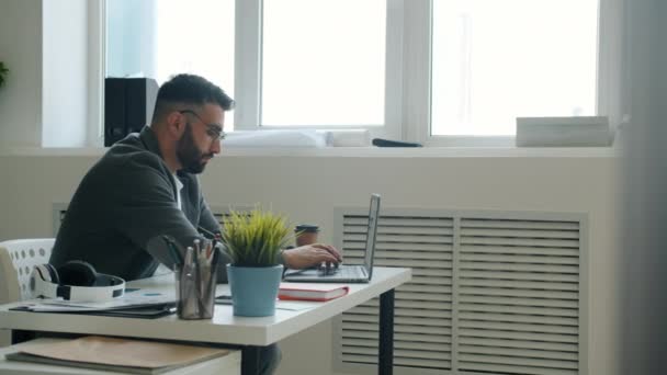 Fou employé de bureau en utilisant un ordinateur portable frappant table avec les poings et s'éloignant du lieu de travail — Video