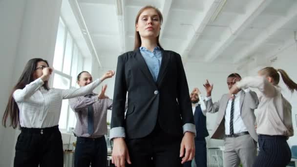 İş arkadaşları dans ederken, ciddi bir yüzle ofiste duran hırslı bir kadının düşük açılı çekimi. — Stok video