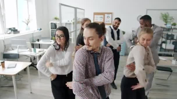 Karışık ırklardan oluşan bir grup iş adamı ofiste birlikte dans ederek eğleniyor ve takım çalışmasının tadını çıkarıyor. — Stok video