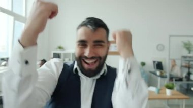 Mutlu iş adamı kameraya bakıp dans ediyor sonra da işyerine yürüyor.