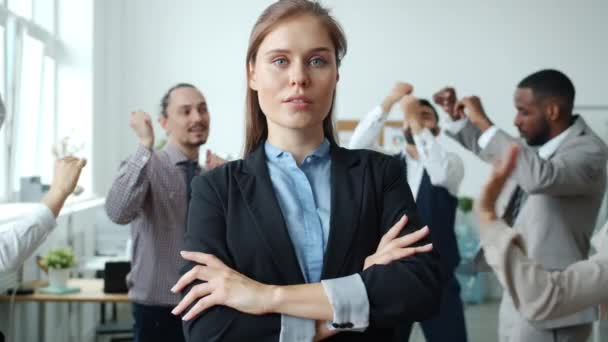 Ανεξάρτητη επιχειρηματίας κυρία στέκεται στο χώρο εργασίας με σοβαρό πρόσωπο, ενώ οι συνάδελφοι χορεύουν διασκεδάζοντας — Αρχείο Βίντεο