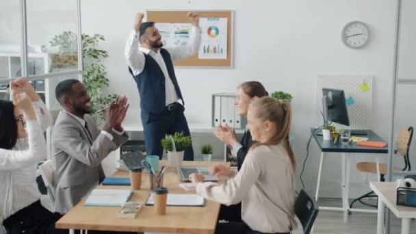 Grupo de empresários dançando em torno da mesa de trabalho celebrando um acordo de negócios bem sucedido — Vídeo de Stock