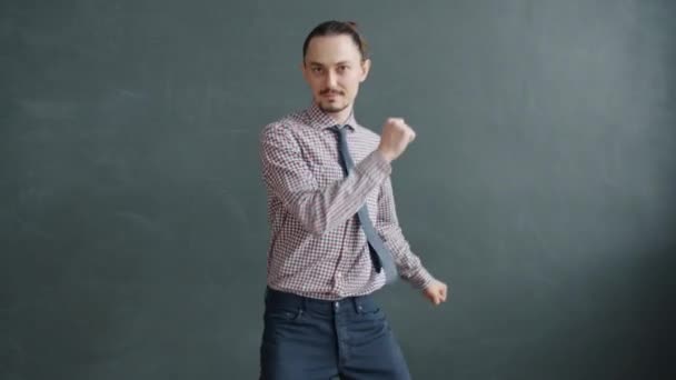 Porträt eines hübschen jungen Mannes, der vor grauem Hintergrund tanzt und Spaß hat — Stockvideo