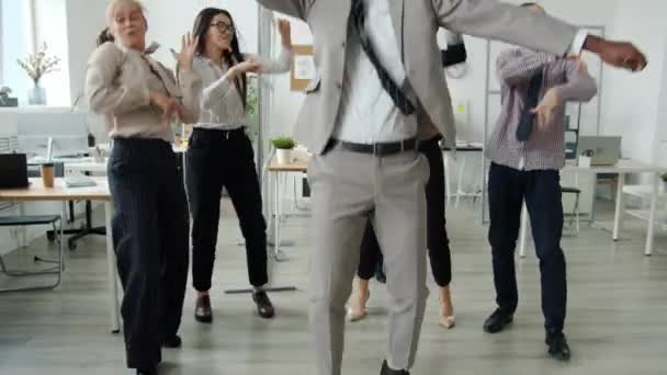 Carefree men and women in formal clothing dancing at business party in coworking area — Stock Video