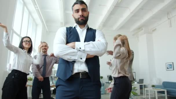 Niski kąt widzenia poważnego właściciela firmy stojącego na imprezie firmowej podczas tańca ludzi — Wideo stockowe