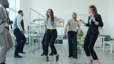 Güzel Asyalı kadın ofis partisinde iş arkadaşlarıyla dans ediyor.