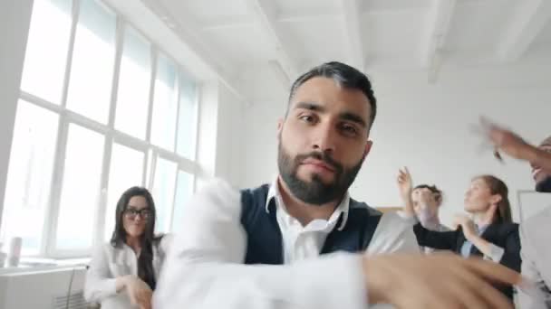 Fröhlicher Chef tanzt und gestikuliert in die Kamera, während Mitarbeiter im Hintergrund feiern — Stockvideo