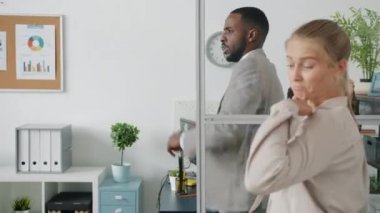 Oyuncu Afro-Amerikalı iş adamı ofiste çalışanlarla dans ediyor ve eğleniyor.