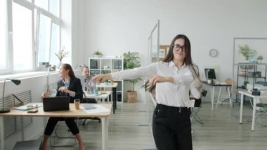 Ofiste dans eden, kameraya gülümseyen neşeli Asyalı iş kadınının yavaş çekim portresi.