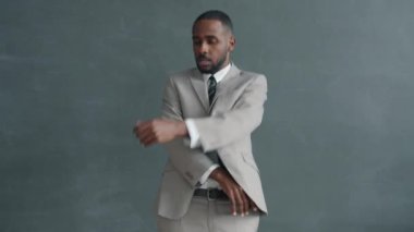 Siyah gri arka planda dans eden takım elbiseli Afrikalı Amerikalı iş adamının yavaş çekim portresi