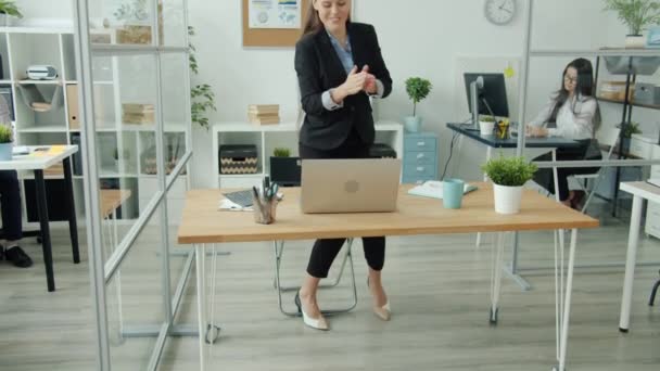 Радісна бізнес-леді, що працює з ноутбуком, потім танцює розважаючись з колегами в офісі — стокове відео
