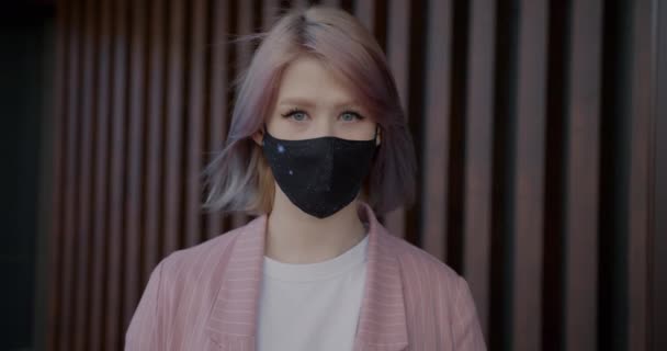 Retrato en cámara lenta de una joven con máscara facial de tela de uso múltiple en el interior — Vídeos de Stock