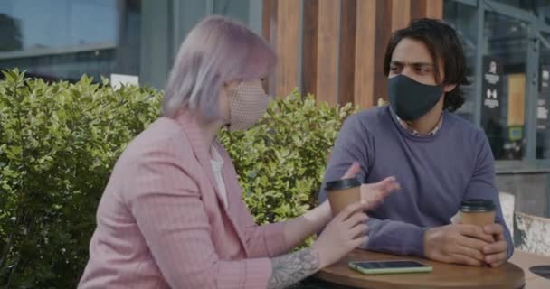 Portrait d'un homme et d'une femme portant des masques parlant à table dans un café pendant une pandémie — Video