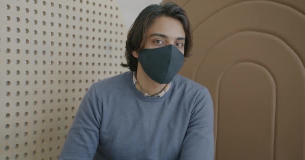 Portret van een goed uitziende Arabier met een beschermend gezichtsmasker binnenshuis — Stockvideo