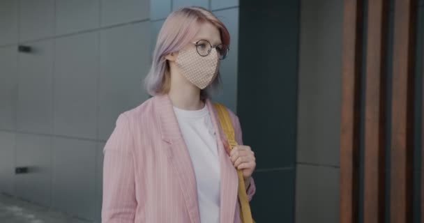 Joven mujer de negocios con máscara facial caminando al aire libre en la calle de la ciudad durante la cuarentena covid-19 — Vídeos de Stock