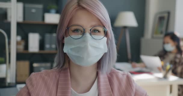 Portrait en gros plan d'une employée de bureau portant un masque facial touchant des lunettes sur le lieu de travail — Video