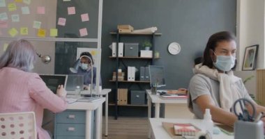Salgın sırasında ofiste çalışan tıbbi maskeli kadın ve erkeklerin yakınlaşması