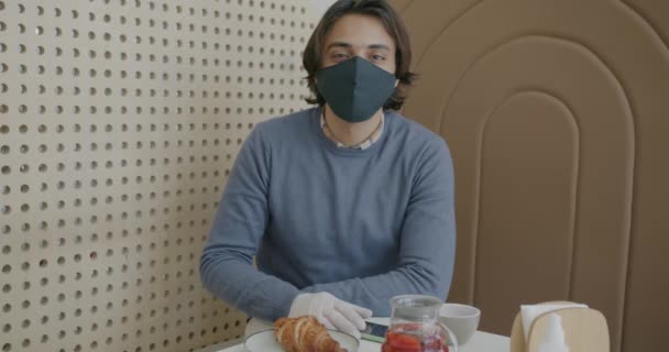 Retrato en cámara lenta del guapo hombre de Oriente Medio usando máscara y guantes en la cafetería — Vídeos de Stock