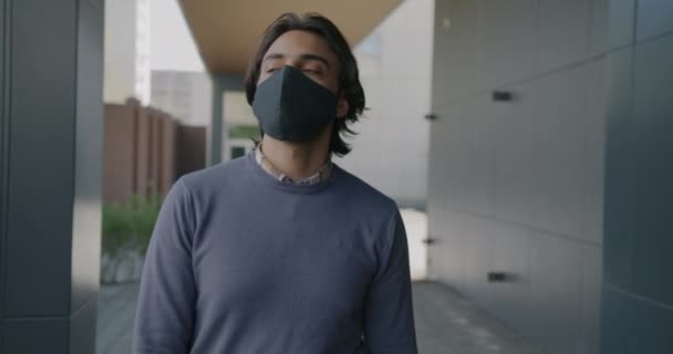 Rallentatore di bello arabo ragazzo indossare faccia maschera a piedi in città strada — Video Stock