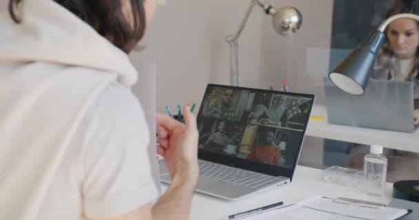 İnternetteki video görüşmesi sırasında ofiste dizüstü bilgisayarla projeyi çeşitli ortaklarla tartışan işadamı — Stok video