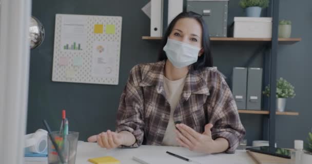 Portrait of cheerful employee talking on video call from office wearing face mask during pandemic — Stock Video