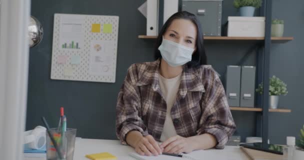 Porträtt av ambitiös kvinna bär ansiktsmask gör online-samtal från kontoret — Stockvideo