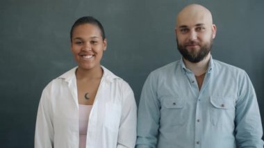 Neşeli insanların portresi Afro-Amerikalı kadın ve siyah arka planda duran beyaz adam gülümsüyor.