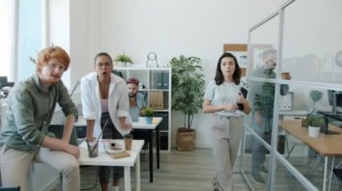 Duygusal ofis çalışanları kamerayı gösterip gülüyorlar. İş yerinde komik suratlar yapıyorlar.