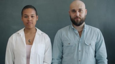 Gri arka planda duran Afro-Amerikalı ve Kafkasyalı ciddi gençlerin portresi