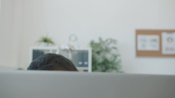 Close-up retrato de mulher afro-americana levantando a cabeça sobre tela do computador sorrindo mão acenando — Vídeo de Stock