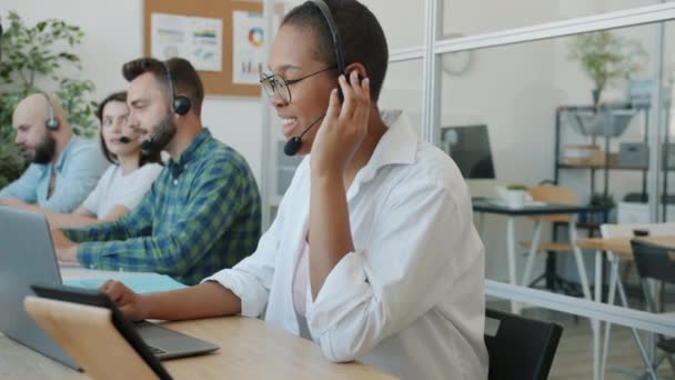 Karışık ırk grupları çağrı merkezinde çalışıyor ve iletişim ile meşgul dizüstü bilgisayarlar kullanarak müşterilerle konuşuyor. Teknoloji ve pazarlama kavramı. — Stok video