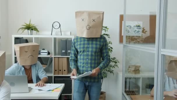Skupina lidí s papírovými taškami na hlavách, kteří pracují v úřadu a vyjadřují emoji emoce — Stock video
