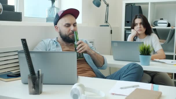 Чоловік алкогольний офіс працівник п'є з пляшки, а потім розмовляє з сердитим колегою — стокове відео
