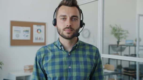 Portrait au ralenti d'un beau mec portant un casque avec un microphone debout au bureau — Video