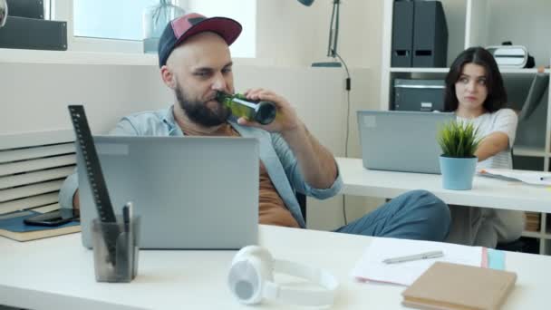 Beztroski człowiek pijący alkohol w pracy walczący z kolegą a potem śpiący — Wideo stockowe