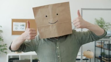 İş yerinde gülümseyen emojili ekmek torbası takan iş adamının portresi.