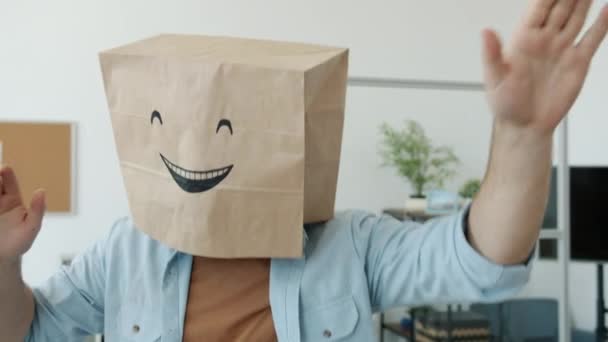 Zpomalený portrét veselého zaměstnance v pytli na chleba s emoji na hlavě tančící v kanceláři — Stock video