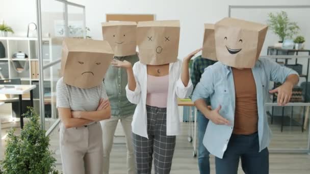 Zpomalený portrét lidí v pytlích na chleba s emoji tančící v kanceláři vyjadřující různé emoce — Stock video