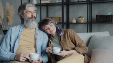 Olgun bir adam ve orta yaşlı bir kadın kahve içip evdeki kanepede gevşeyerek konuşuyorlar.