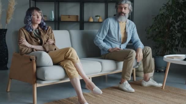 Homem e mulher sentados no sofá com rostos zangados suspirando expressando emoções negativas — Vídeo de Stock