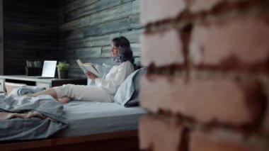 Güzel bayan evde kitap okumaktan zevk alıyor evde yalnız başına rahat pijamalar giyiyor.