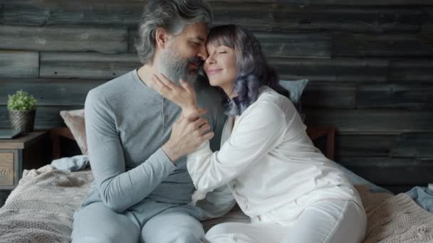Amante casal abraçando acariciando uns aos outros expressando ternura sentado na cama juntos — Vídeo de Stock