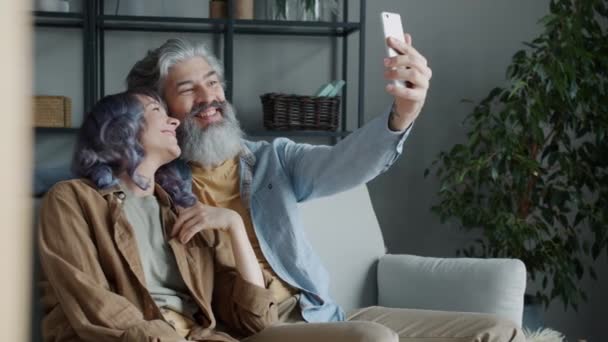 Casal feliz conversando e acenando mão fazendo videochamada online com smartphone em casa — Vídeo de Stock
