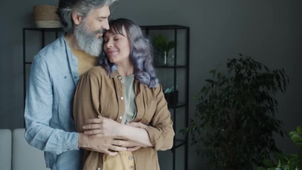 Movimento lento de pessoas felizes casal abraçando e beijando expressando amor de pé em casa juntos — Vídeo de Stock