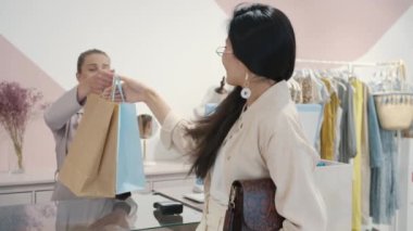 Asyalı kadının alışveriş çantalarını tezgahtardan alıp yürümesi.