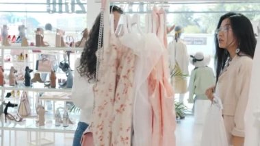 Zarif Asyalı kadın giysi alışverişi yapıyor. Tabletli satıcı kadınla konuşuyor.