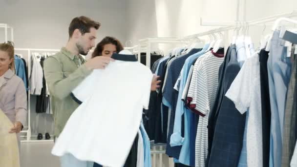 Hombre adicto a la compra de ropa y peleas con su esposa en la tienda de moda — Vídeo de stock