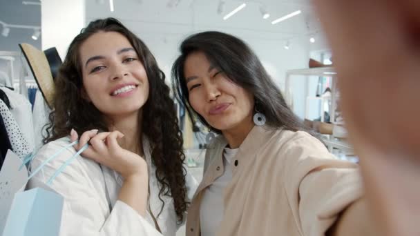 Retrato de meninas alegres amigos tirando selfie na loja de moda segurando sacos fazendo caras engraçadas — Vídeo de Stock