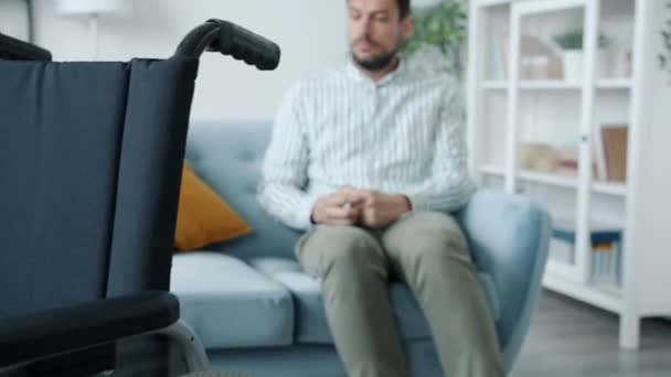 Zoom-Porträt eines einsamen Behinderten, der beim Anblick eines an Depressionen leidenden Rollstuhls weint — Stockvideo